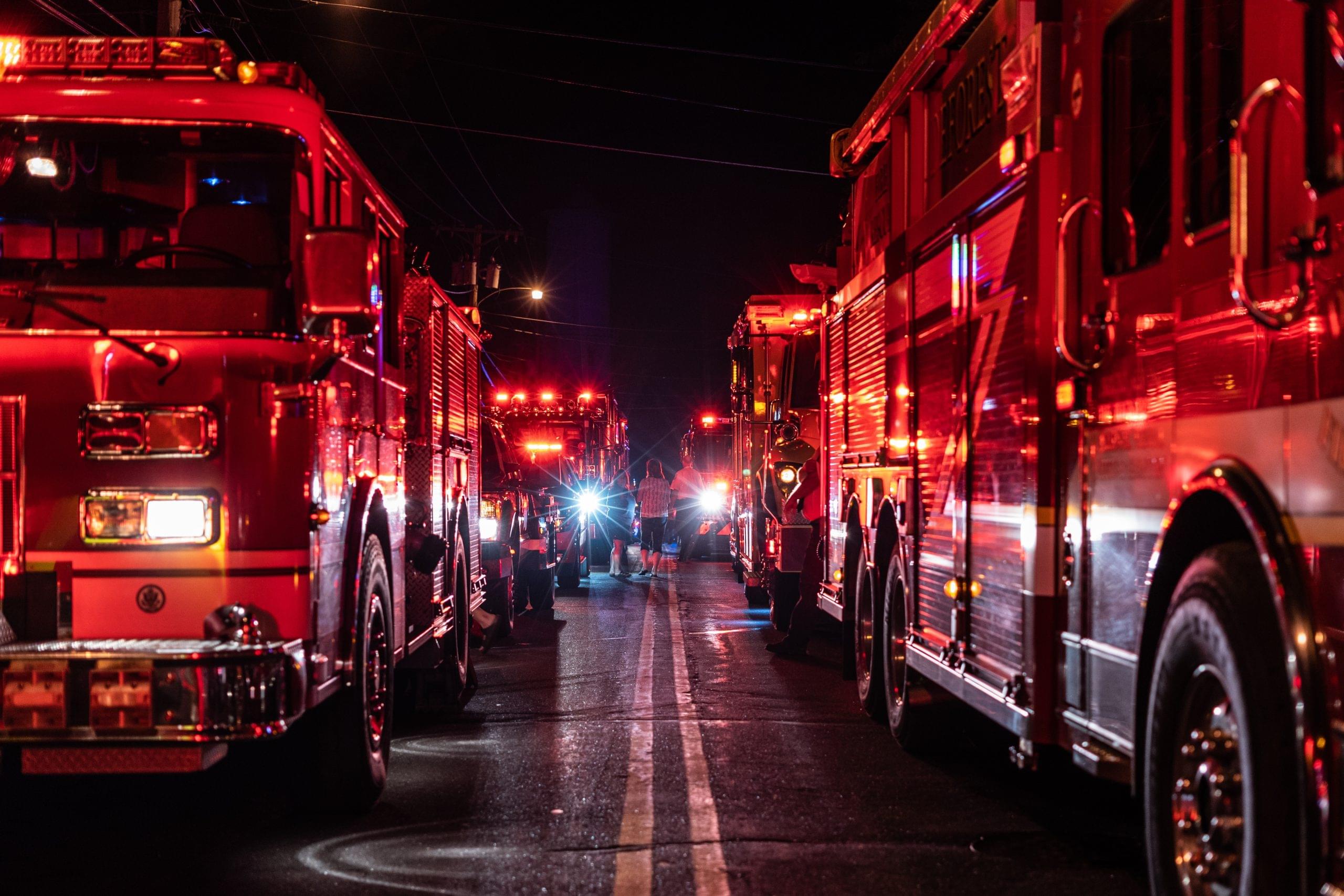 Firetrucks lining a street at night